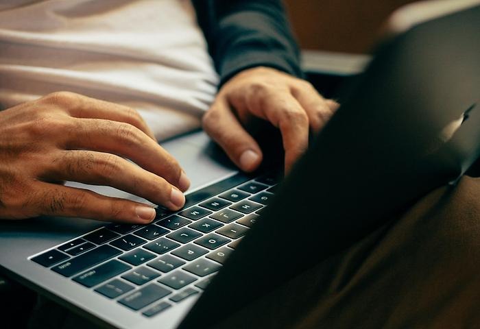 Händer som skriver på tangentbord på laptop