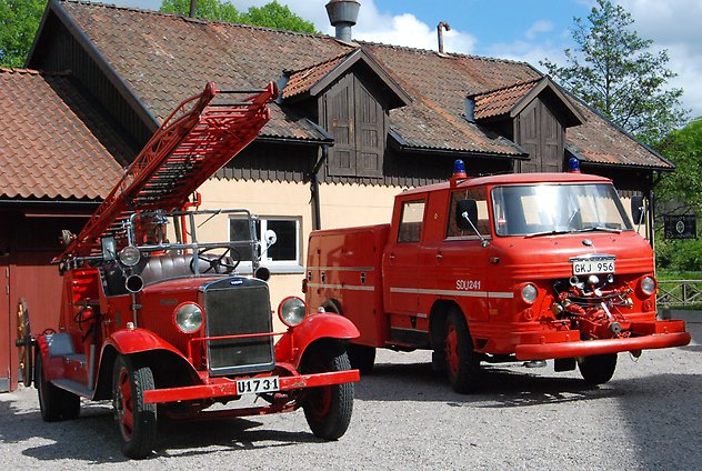 Två röda brandbilar står framför en byggnad