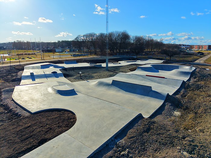 Stor betongrullpark med ramper och bowls i en parkmiljö.