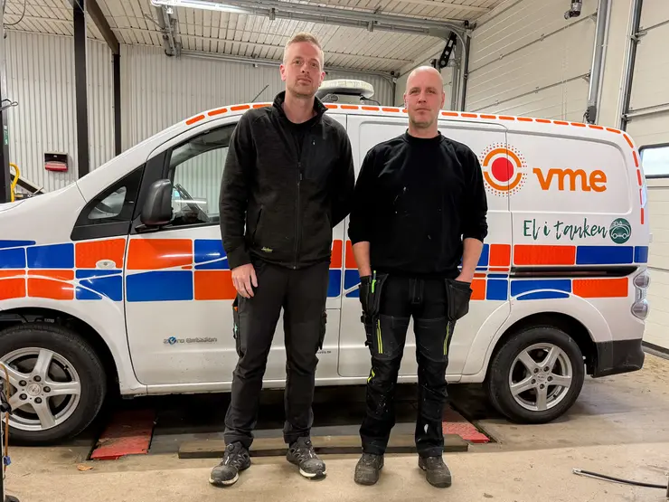Två personer i verkstad framför vit VME-servicebil.